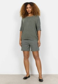 Haut vert olive à manches courtes avec une coupe décontractée, associé à un short assorti. L'ensemble présente un tissu doux et peu de détails.