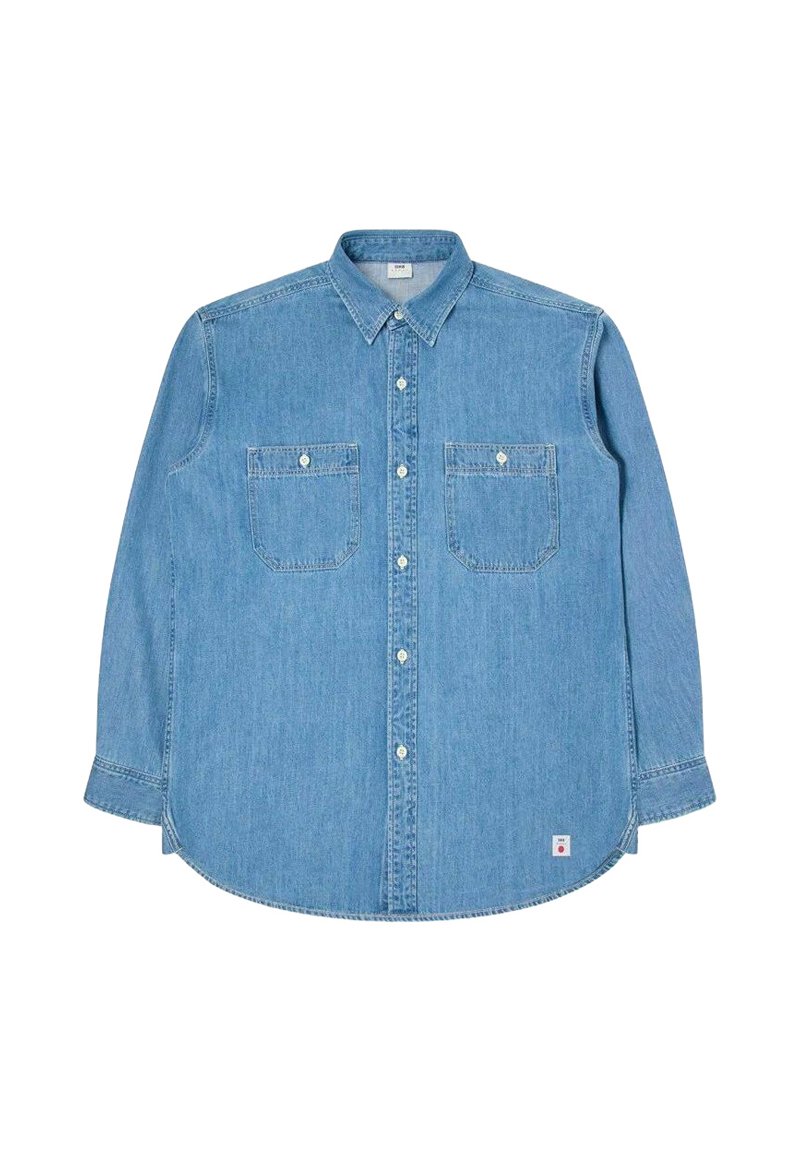 Lys blå denim langærmet skjorte med button-down krave, to brystlommer og hvide knapper. Har et buet kant og diskrete syninger.