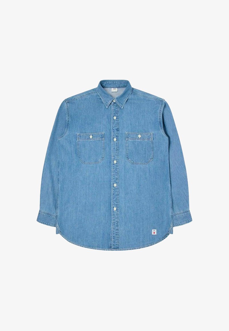 Lys blå denim langærmet skjorte med button-down krave, to brystlommer og hvide knapper. Har et buet kant og diskrete syninger.