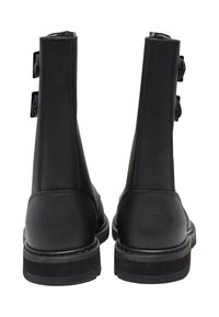 Botas negras hasta el tobillo con textura suave, que cuentan con dos hebillas en el lado exterior y una suela de goma resistente.