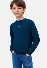 Felpa blu navy con colletto rotondo, caratterizzata da un logo sul petto e toppe testurizzate sulle maniche. Abbinata a jeans blu.