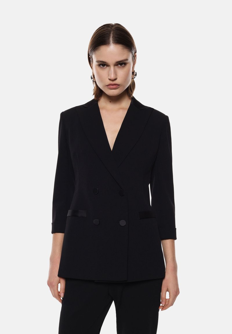 Blazer nero doppiopetto con rever arosa, maniche a tre quarti, dettagli in satin e due tasche frontali. Realizzato in un tessuto strutturato.