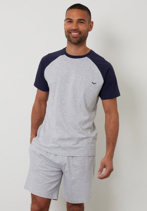 Graues Jerseyt-Shirt mit marineblauen Raglan-Ärmeln, kombiniert mit passenden grauen Shorts. Verfügt über ein kleines Logo auf der oberen linken Seite des Shirts.