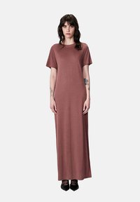 Abito maxi in colore rosa tenue, realizzato in tessuto morbido. Dispone di maniche corte e di un semplice scollo rotondo. Texture liscia, lungo fino alla caviglia.
