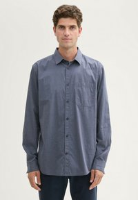 Langärmliges, dunkelblaues Button-up-Hemd mit subtiler Struktur, einer Brusttasche und einem klassischen Kragen, aus leichtem Stoff gefertigt.