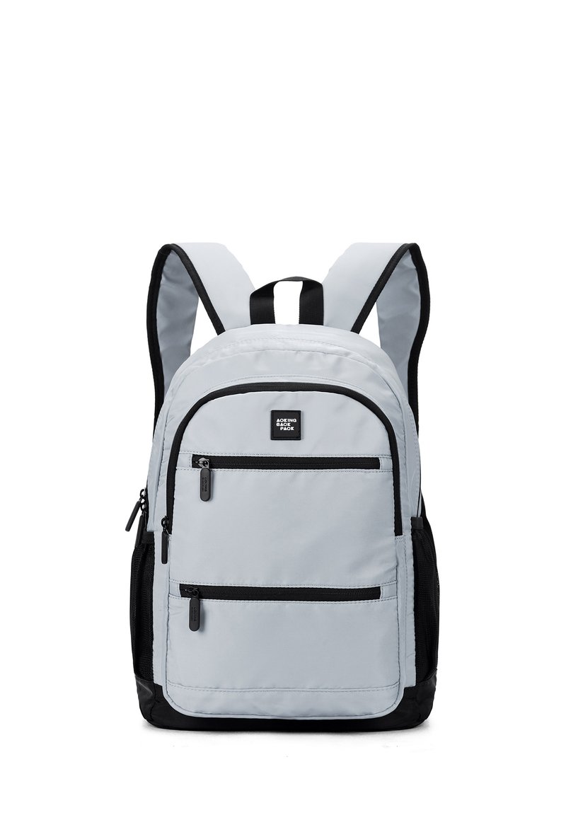 Zaino in tessuto grigio chiaro con accenti neri, dotato di due tasche frontali con zip, spallacci regolabili e una maniglia superiore per il trasporto.