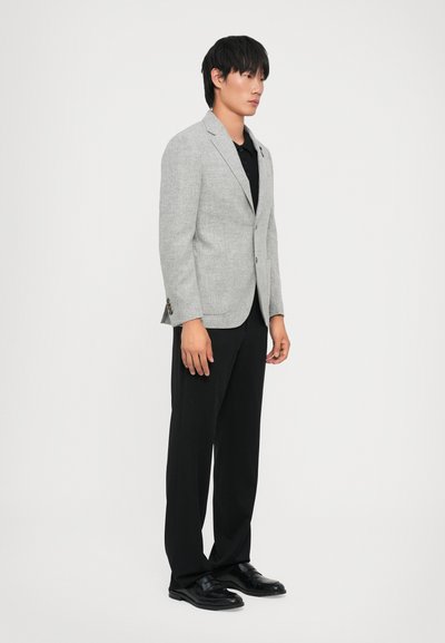 Light gray blazer with a textured finish, single-button closure, paired with a black shirt and black trousers, worn with black shoes.