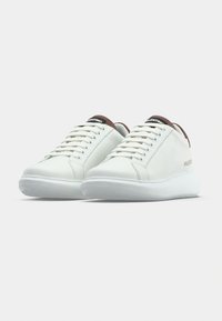 Λευκά δερμάτινα αθλητικά παπούτσια με λείο φινίρισμα, με στρογγυλά κορδόνια και αντίθετο καφέ ταμπάκ στην φτέρνα. Λαστιχένια σόλα με υφή για καλύτερο κράτημα.