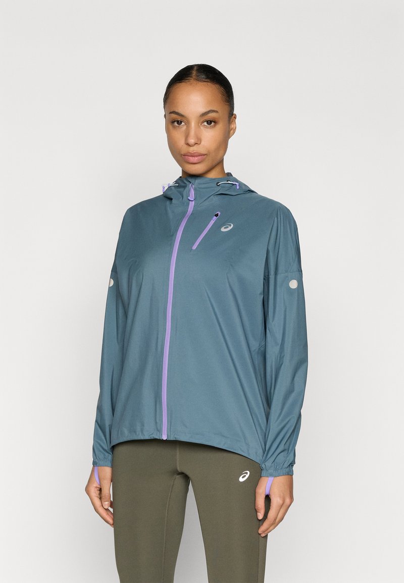 Ελαφρύ, τιρκουάζ τζάκετ για τρέξιμο με κουκούλα, μωβ φερμουάρ και ρυθμιζόμενα κορδόνια. Διαθέτει ελαστικά μανίκια και αντανακλαστικό λογότυπο.