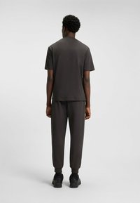 T-shirt corto a maniche corte grigio scuro e pantaloni affusolati abbinati con polsini a coste. Realizzati in un materiale liscio e leggero. Calzature: sneaker nere.