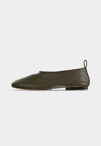 Chaussure plate en cuir marron foncé à enfiler, avec un bout arrondi, un petit talon et une languette à l'arrière, vue de profil sur fond uni.