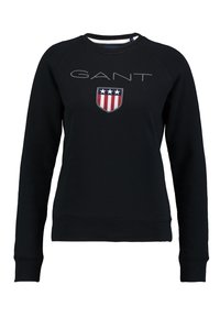 Sudadera negra de algodón con cuello redondo, que presenta un logo en relieve de "GANT" y un escudo bordado con acentos en rojo, blanco y azul.