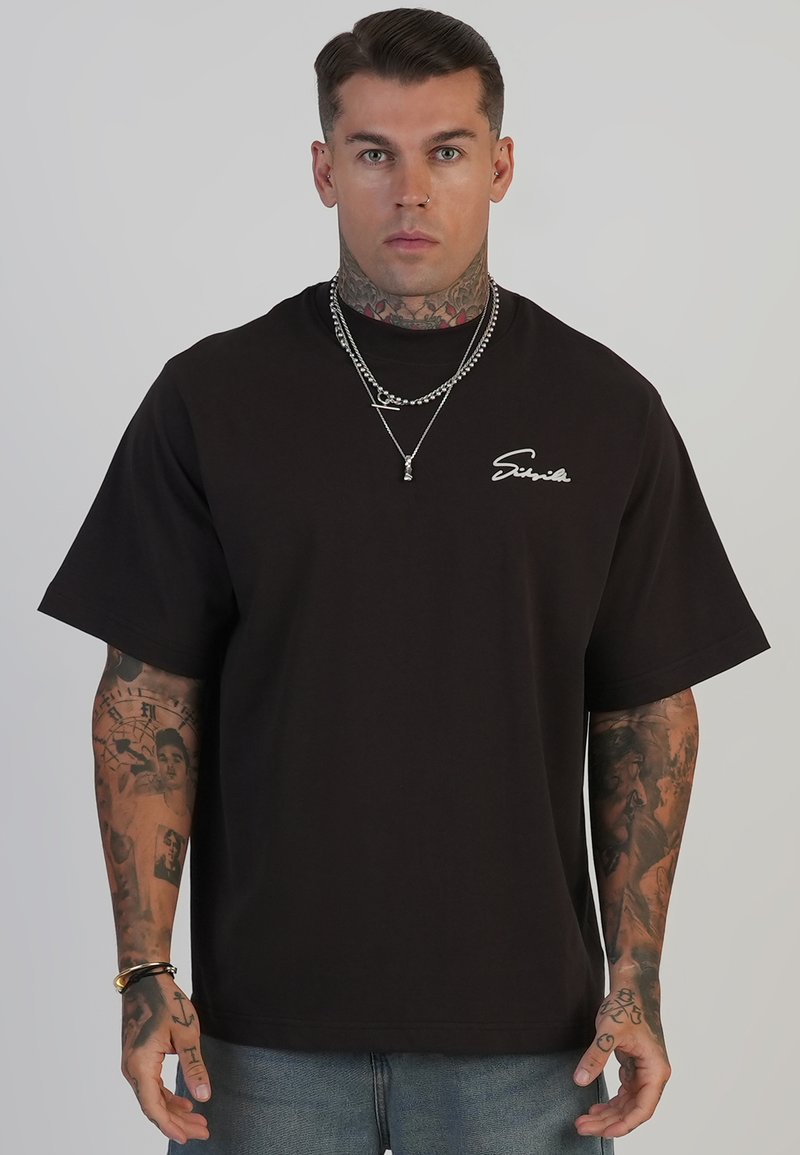 Sort bomulds T-shirt med korte ærmer og rund halsudskæring, med hvid signatur tekstdesign på brystet. Casual pasform, minimal dekoration.
