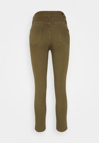 Vaqueros skinnies verde oliva con cintura de media altura, cinco bolsillos y detalles de costura. Textura suave y líneas limpias a lo largo.