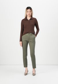 Brown ribbed long-sleeve polo shirt paired with olive green slim-fit trousers and tan high-heeled shoes. Simple, structured design.