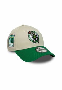 Beige Baseballkappe mit grünem Schirm, mit dem Logo der Boston Celtics und Patches. Hergestellt aus Stoff, hat sie einen verstellbaren Riemen auf der Rückseite.