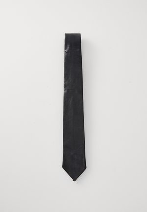 Corbata de cuero negro con una textura suave, que presenta una punta afilada y un diseño minimalista. Cuelga verticalmente sobre un fondo blanco.