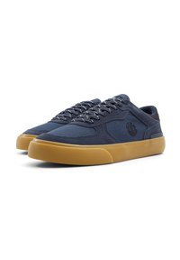 Zapatillas de lona navy con suela de goma texturizada, punta redondeada, suela marrón contrastante y cordones a juego que presentan un logo en el lateral.