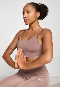 Conjunto de soutien azul e leggings em tecido liso e elástico. Apresenta um design ajustado e detalhes de logotipo perto da bainha do soutien.
