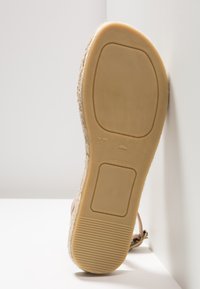 Beige espadrille sandal med en texturerad juteöverdel, gummisula och präglad storlek '37' på undersidan. Hållbar, med en platt häldesign.