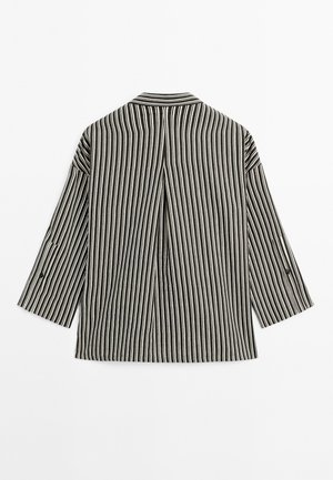 Black and white striped jacket with three-quarter sleeves, featuring a classic collar and a center back pleat for added structure.