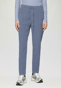 Lichtblauwe joggingsbroek met een elastische tailleband, trekkoord, zijzakken en een relaxte pasvorm, gecombineerd met zilveren sportschoenen.