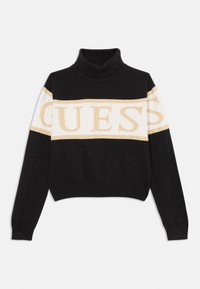 Črn skrajšan pulover s turtleneck ovratnikom, ki ima zlate in bele "GUESS" logotipe na prsih ter rebraste manšete. Mehak pleten material.