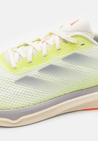 Light green and white Adidas running shoe with mesh fabric, white laces, three silver stripes, and "Dreamstrike+" sole detail.