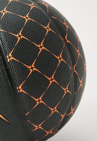 Sort basketball med en tekstureret overflade, der har et geometrisk orange mønster og sorte gummidetaljer. Glat finish, rund form.