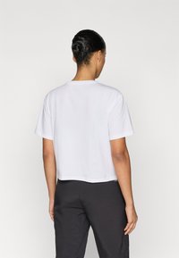 Άσπρο κοντομάνικο τοπ, κατασκευασμένο από απαλό βαμβάκι, με κλασικό στρογγυλό λαιμό και απλό, καθαρό σχέδιο.