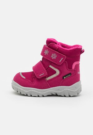 Pink children's boots with a suede texture, featuring two Velcro straps, snowflake details, and a rugged gray sole. Waterproof GORE-TEX design.