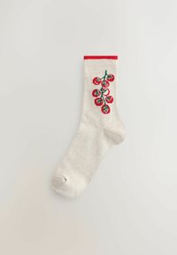 Knee-high sock in cream with a red cuff. Features a green vine design with red floral accents. Made of ribbed knit fabric.