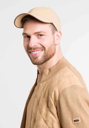 Beige cap with a smooth texture, paired with a quilted beige sweater featuring diamond patterns and a ribbed collar.
