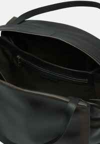 Czarna skórzana torba tote z zamkiem błyskawicznym, wyposażona w wewnętrzną kieszeń i gładką teksturę. Solidne uchwyty do łatwego noszenia.