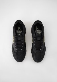 Czarne buty sportowe z teksturowaną siateczką i syntetycznymi nakładkami, wyposażone w odblaskowe akcenty i sznurowadła, oznaczone jako "New Balance 1000".