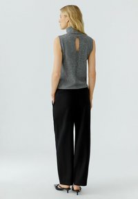 Gray sleeveless turtleneck with a back keyhole detail, paired with black wide-leg pants and black slip-on shoes. Smooth texture and fitted design.