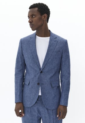 Blazer en lin bleu clair mélangé avec des revers crantés, fermeture à un bouton et deux poches avant, associé à un t-shirt blanc à col rond.