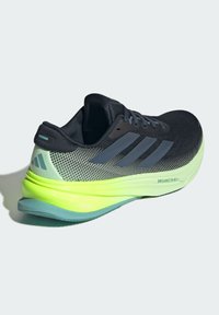 Černá a zelená sportovní obuv s síťovinovým svrškem, výrazným designem tří pruhů a silnou, polstrovanou podrážkou s brandingem "DREAMSTRIKE".