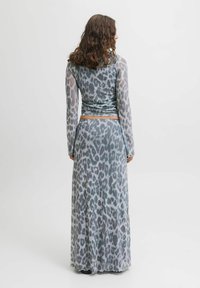 Abito lungo grigio con stampa leopardata, dotato di un corpetto aderente e maniche lunghe trasparenti. Il tessuto ha una texture liscia e scivola fino a una lunghezza maxi.