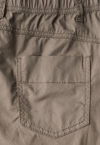 Pantaloni corti marroni con vita elastica, caratterizzati da una singola tasca posteriore rettangolare con dettagli cuciti. Il materiale è morbido e leggermente strutturato.
