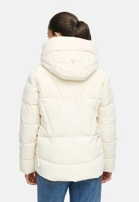 Doudoune blanche avec capuche, présentant des panneaux matelassés et un logo au dos. Le tissu est lisse et de finition mate.