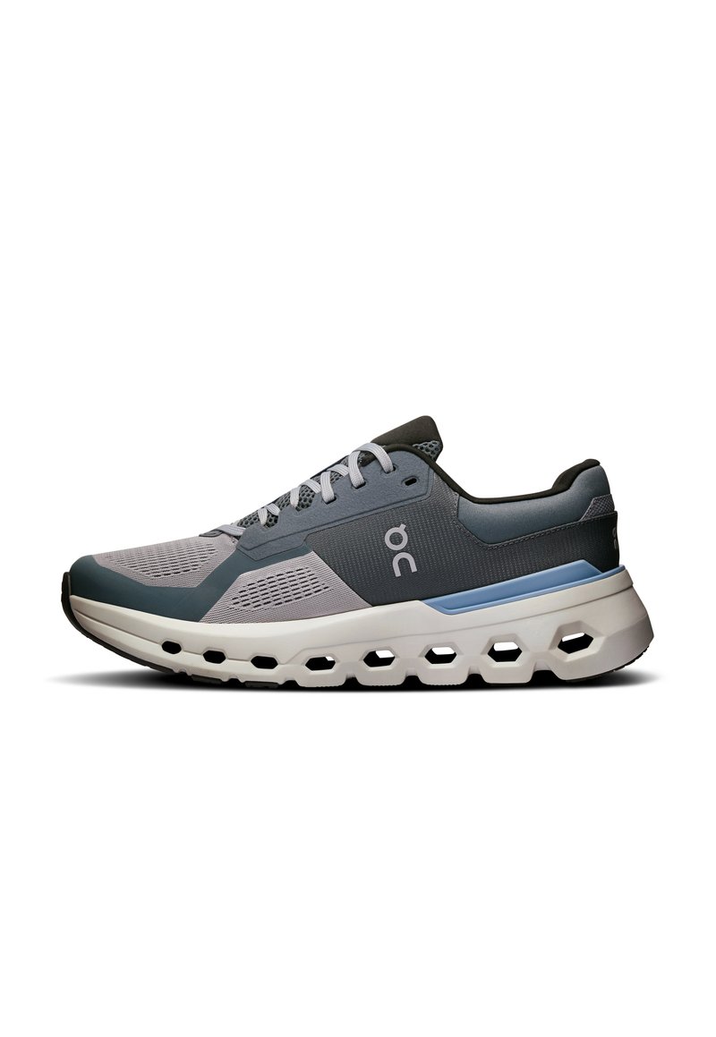 Grauer und blauer Sportschuh mit Obermaterial aus Mesh, gepolsterter Sohle mit hexagonalen Ausschnitten und Schnürsystem für Unterstützung und Belüftung.