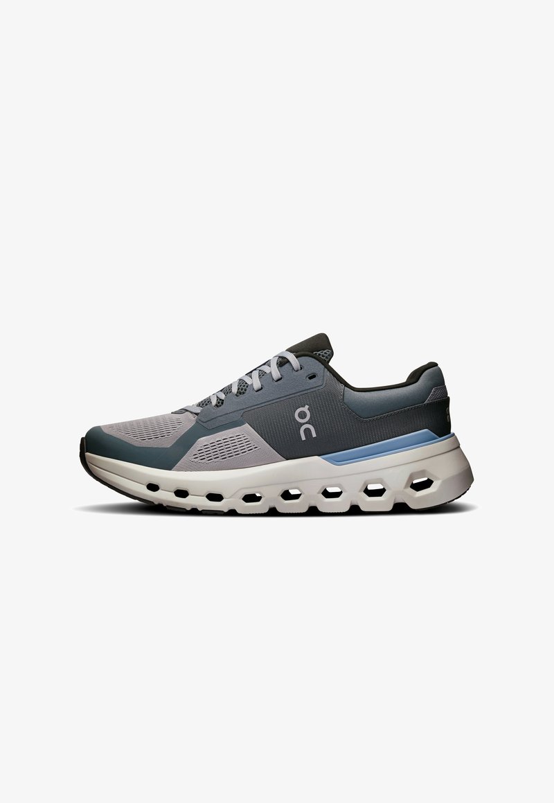 Scarpa sportiva grigia e blu con tomaia in rete, suola ammortizzata con fori esagonali e sistema di allacciatura per supporto e ventilazione.