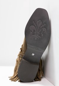 Brązowe zamszowe mokasyny z frędzlami, płaską czarną gumową podeszwą i wytłoczonym kwiatowym wzorem. Etykieta rozmiaru wskazuje "39."