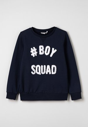 Sweat-shirt bleu marine à col rond, poignets et ourlet côtelés. Présente un texte blanc duveteux "#BOY SQUAD" en évidence sur le devant. Matière douce.