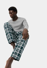 Gray long-sleeve shirt and green plaid pajama pants in soft fabric. Pants feature white and navy patterns, loose fit, and cuffed hems.