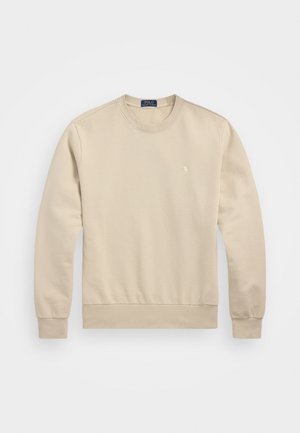 Beige sweatshirt tillverkad av mjukt bomullsmaterial. Har rund halsringning, långa ärmar och en liten logotyp på vänster bröst.