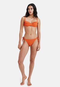 Bikini portocalie cu textură cu nervuri, cu sutien cu suport și fund cu șnur ajustabil pe lateral. Textură netedă, hardware minim și design ajustat.