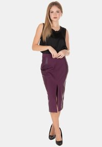 Gonna a matita viola con spacco frontale, realizzata in tessuto liscio. Abbinata a un top nero senza maniche e a tacchi alti neri.