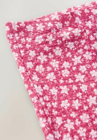 Rosa Textil mit einer strukturierten Oberfläche, das ein weißes florales Muster aufweist. Der Stoff ist leicht und sanft zerknittert.
